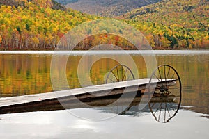Serene autumn fall foliage reflection on lake with dock