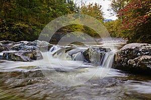 Serene Autumn River Flow with Silky Water Effect and Lush Foliage