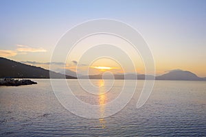 Serene bay on Greek coast with the sun setting behind distant mountains