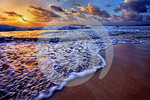 Serene beach destination sunrise with breaking wave crest and sea foam