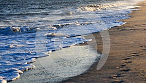 A Serene Beach with Gentle Waves Caressing the Shore with the light of the setting sun reflecting off