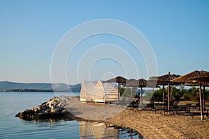 Serene beach setting with loungers and cabanas on a sunny day near the water photo