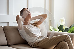 Serene beautiful woman with closed eyes resting on cozy sofa