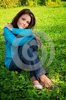 Serene beautiful woman resting on green grass