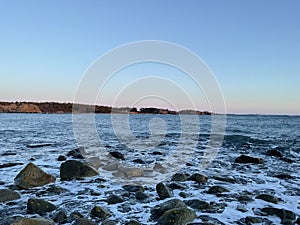 Serene body of water with rocks against the backdrop of a blue sky