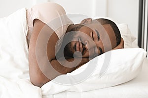 Serene calm young black man sleeping well alone in bed