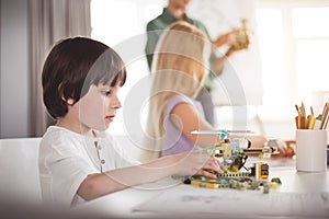 Serene child creating robot at desk