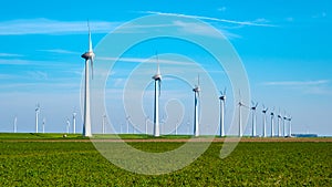 A serene green field is adorned with a row of sleek windmills, their blades gracefully turning in the gentle breeze of