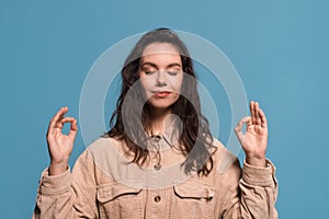 Serene happy pretty young european woman with closed eyes meditates, enjoys silence and relaxation