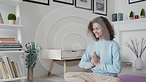 Serene healthy young woman meditating at home watching online yoga class.