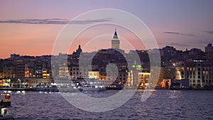 A serene journey by boat at dusk offers a striking view of Istanbul's iconic Galata Tower, rising majestically