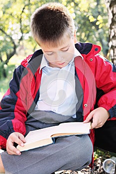 Serene kid reading book in park