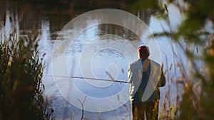 Serene Man Enjoying the Early Morning Fishing Experience by the Calm Lake at Sunrise, Surrounded by the Beauty of Nature