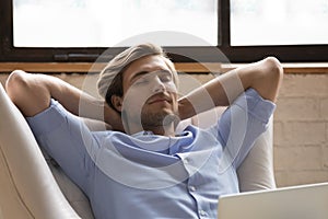 Serene man relaxing lean on cozy armchair with laptop