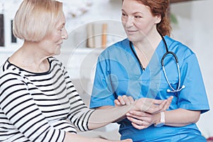 Serene nurse checking heartbeat and pulse of elderly patient