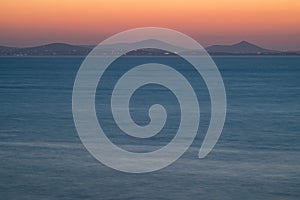 Serene Ocean Sunset with Distant Mountains