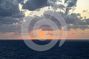 Serene ocean sunset with dramatic clouds.