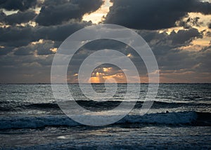 Serene ocean sunset with dramatic clouds.