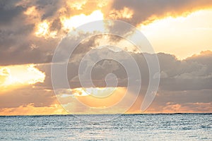 Serene ocean sunset with dramatic clouds and sun rays.