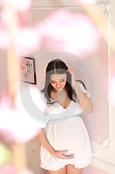 serene pregnant in a white dress on pink background