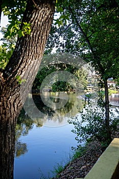 A serene river scene featuring a small stone dam with water gently cascading over the edge photo