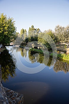 A serene river scene featuring a small stone dam with water gently cascading over the edge photo