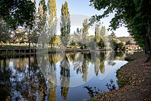 A serene river scene featuring a small stone dam with water gently cascading over the edge photo