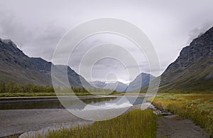 Serene river scenery in mist atmosphere streaming in between rapadalen mountain valley