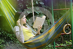 Serene scene with teen girl in hammock with apricot reading book