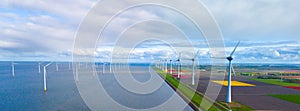 A serene scene unfolds as wind mills stand tall around a vast lake, harnessing the power of the wind in the Netherlands