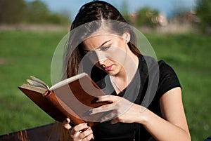 Feliz mujer joven lectura su popular un libro en sobre el soleado 