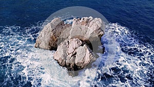Serene sea with rock, breaking wave caresses. Tranquil, clear blue sea, rock central, breaking waves gentle touch. Each