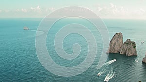 Serene Seascape with Sailing Vessel and Rocky Outcrops. Sailboat traces sea waves near monumental stone formations