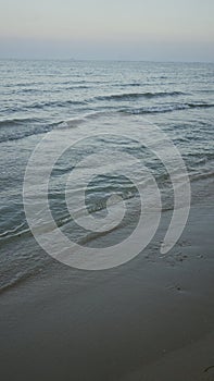 Serene seaside promenade with gentle waves and sandy shore at twilight