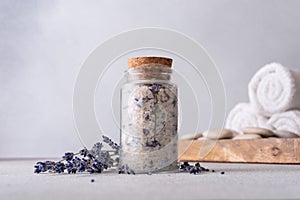 A serene spa setting with a glass jar of aromatic lavender salt sealed with a cork, surrounded by scattered lavender flowers,