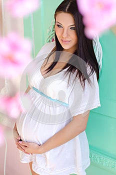 serene spring pregnant in a white dress on a turquoise backgrou