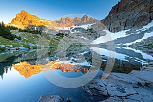 Serene sunrise at mountain lake with snowy peaks reflection
