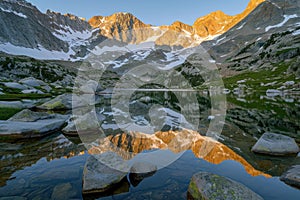 Serene sunrise at mountain lake with snowy peaks reflection