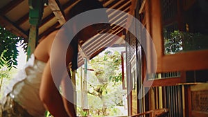 Serene tropical setting with a woman cleaning the wooden desk, surrounded by lush greenery