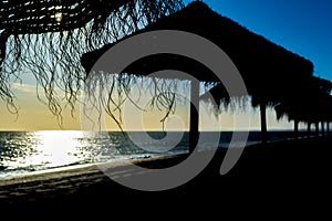 Serene vacation beach setting during a sunset with silhouetted sunshades photo