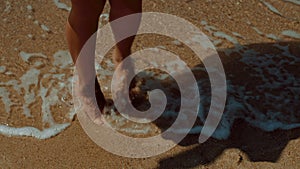 A serene video of a person walking barefoot on a sandy beach, with their feet in the water. Enjoy the peaceful vibes of