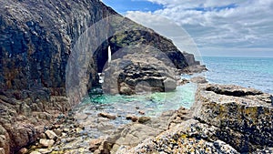 Serene view of a beach with clear blue ocean water and rocky shoreline in Cornwall.