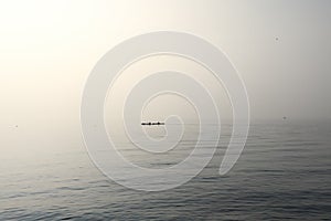 A serene vista captures two canoes gliding over Lake Garda placid waters, enveloped in the soft embrace of morning fog,