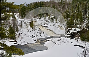 Serene winter scene of a river flowing through snow-covered forest. Sudbury, Canada. photo