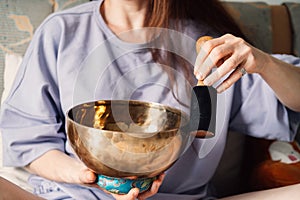 A serene woman practices sound healing using a singing bowl, immersed in a moment of meditative