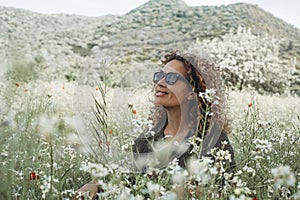 Serene woman sitting in the meadow with white blossom flowers around. Relaxation and mindfulness healthy lifestyle. People