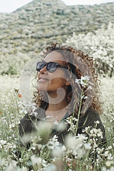Serene woman sitting in the meadow with white blossom flowers around. Relaxation and mindfulness healthy lifestyle. People