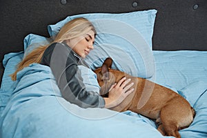 Serene woman sleeping with French bulldog in bedchamber