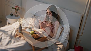 Serene woman texting mobile phone in morning. Relaxed girl enjoying breakfast