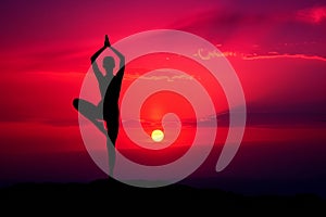 Serene yoga tree pose silhouette gracing a dramatic red sunset horizon